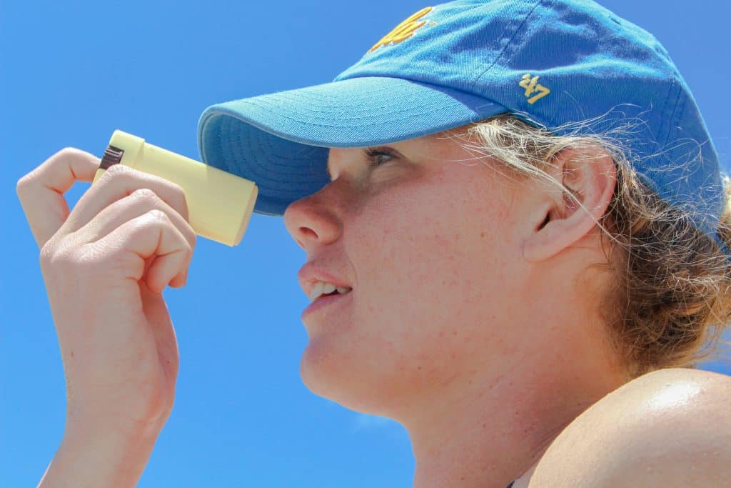 un jeune homme avec une casquette entrain de de s'appiquer un stick de crème solaire